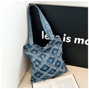 Detail of blue denim tote bag featuring fringed squares and star patterns on a display