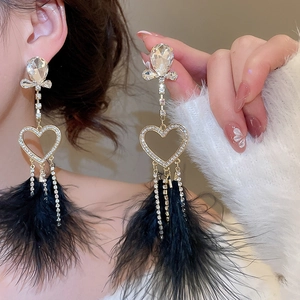 Detail view of long tassel earrings with sparkling crystals and black feather fringes