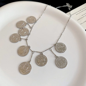 Detail of silver vintage multi-coin pendant necklace with embossed portrait charms