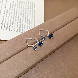 Detail of silver U-shaped hoop earrings with dangling navy blue star zircon pendants