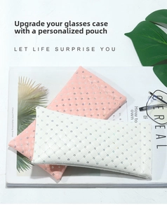 Quilted PU leather sunglasses pouches in white and pink with glitter accents on a magazine