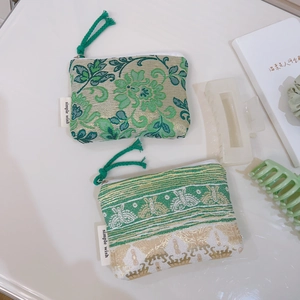 Detail of jacquard floral coin purses with green woven zipper pulls and brand label