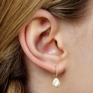 Close-up of elegant baroque pearl earrings with gold hoop on model showing refined details