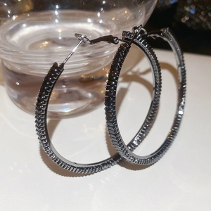 Macro shot of large gunmetal hoop earrings encrusted with sparkling black cubic zirconia