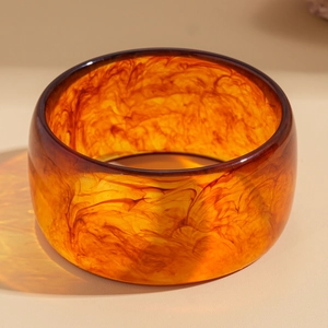 Macro shot of amber resin bangle showing detailed smoky tortoise patterns and textures