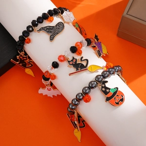 Detalle de pulseras de cuentas de Halloween con dijes de calabaza, fantasma y gato en soporte