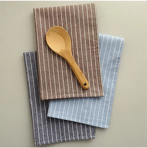 Detail view of striped cotton kitchen towels in brown and blue with a wooden spoon accessory