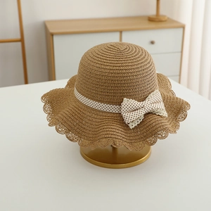 Close-up of girl straw sun hat featuring wavy brim and delicate lace bow detail