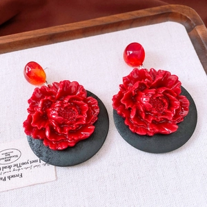 Detailed macro view of vintage red wooden flower drop earrings on a light wooden surface