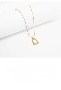 Macro detail of golden geometric hollow pendant necklace with polished mirror surface