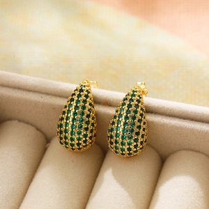 Macro view of gold teardrop earrings with pavé green cubic zirconia on velvet box
