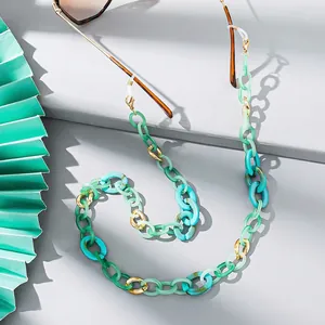 Detail of mint green acrylic and gold metal links on a stylish sunglasses chain strap
