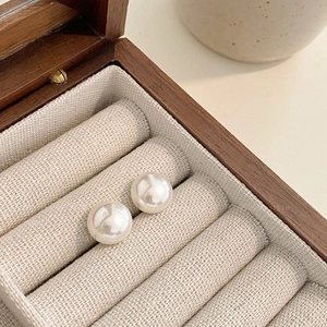Detailed macro view of white lustrous round pearl earrings in a wooden jewelry gift box