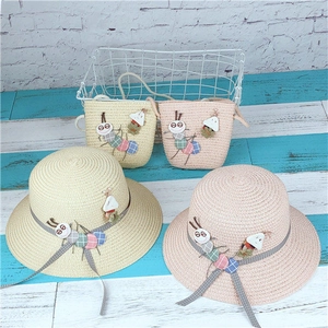 Detail view of woven straw sun hat and matching bag with colorful caterpillar applique