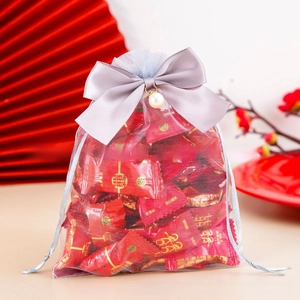 Close-up of gray organza gift bag with a bow and pearl charm for wedding candy