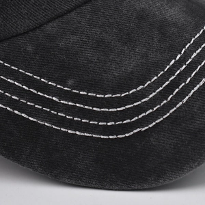 Detail of contrast stitching and washed cotton texture on the black baseball cap brim