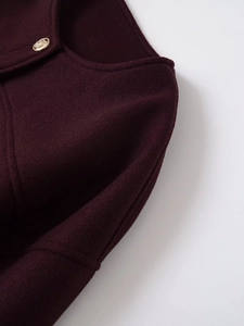 Detailansicht der weinroten Wolljacke mit geprägten goldenen Löwenkopf-Knöpfen