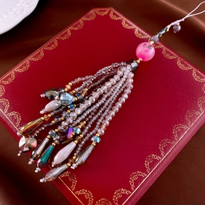 Macro shot of beaded tassel pendant with crystal hearts and amber drops on luxury red box