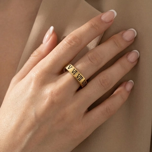 Primo piano dell'anello dorato in acciaio con numeri romani su sfondo di abito