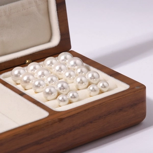 Close-up of white pearl earrings in various sizes arranged in a wooden jewelry box