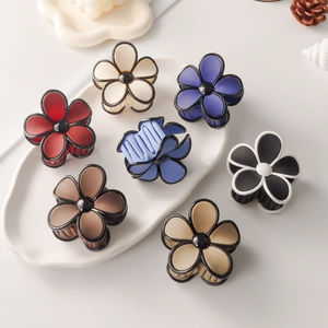 Matte flower hair claws in multiple colors on a white ceramic tray with pine cones