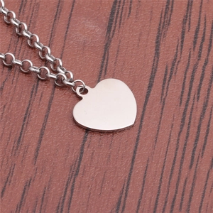 Polished silver titanium steel heart pendant necklace on dark wood background