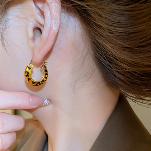 Macro shot of leopard print enamel hoop earring plated in 14k gold on model ear