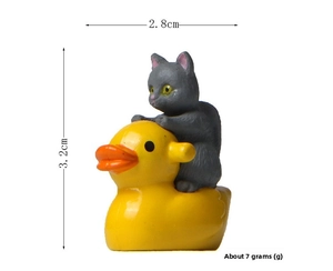 Miniature grey cat riding a yellow duck figurine with dimensions 3.2cm x 2.8cm