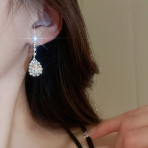 Close-up of sparkling silver drop earrings with transparent crystals worn by a model