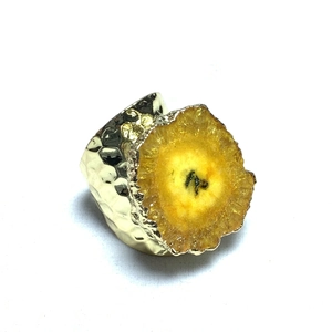 Detalle macro de piedra de cristal amarillo y anillo bañado en oro con textura martillada