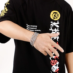 Detail of silver stainless steel NK Cuban chain bracelet styled on a male model wrist