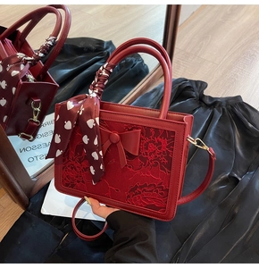 Detail of red leather handbag with floral flocking and silk scarf on handle