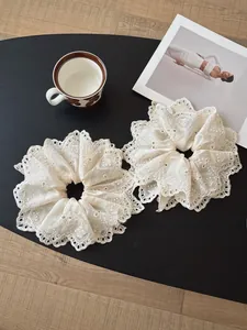 Close-up of beige lace embroidery scrunchies with intricate floral scalloped edges