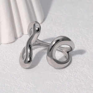 Close-up of a silver irregular streamlined open ring on a textured white surface