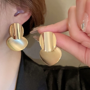 Detail of gold-plated heart star tassel earrings with mirror and matte texture contrast