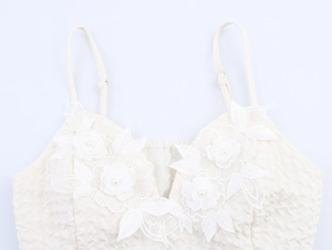 Détail du haut blanc à bretelles avec dentelle florale 3D et décorations de perles