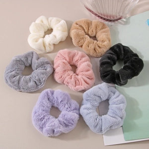 Vista piana di sette elastici per capelli in peluche in vari colori Morandi su un tavolo