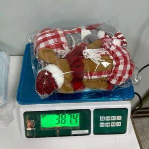 Peluche natalizio con vestito a quadri rossi pesato su bilancia digitale di magazzino