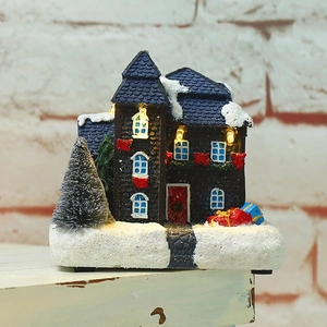 Detailed close-up of a blue glowing Christmas village house on a wooden surface