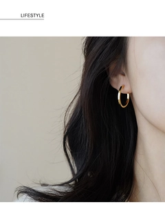 Foto lifestyle di una modella con grandi orecchini a cerchio dorati e stile minimal