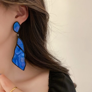 Detail of vintage blue resin teardrop earrings with black metal frame worn by a model