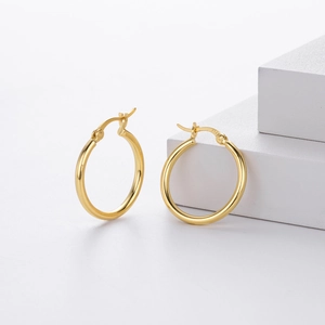 Detailed close-up of 18k gold plated S925 sterling silver hollow tube hoop earrings on white cubes