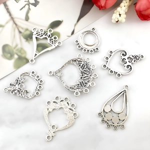 Detailed view of silver alloy DIY earring charms with heart and floral filigree patterns