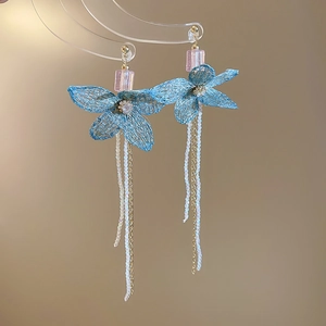 Detail of blue knitted flower earrings with long white pearl tassels and golden chains