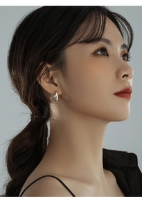 Close-up of minimalist silver water drop hoop earrings worn by a model in a side view