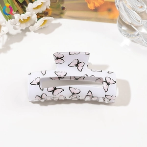 Detail of white butterfly hair claw clip with floral patterns on a clean background