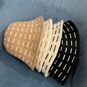 Close-up of three knitted bucket hats in khaki, beige, and black on a blue sofa