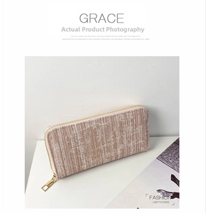 Detail of light pink striped long wallet with gold U-shaped zipper and metal puller