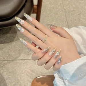 Dettaglio di unghie finte stiletto lunghe con cristalli luccicanti e glitter argento