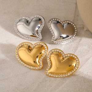 Macro detail of 18k gold and silver heart earrings with sparkling white rhinestones